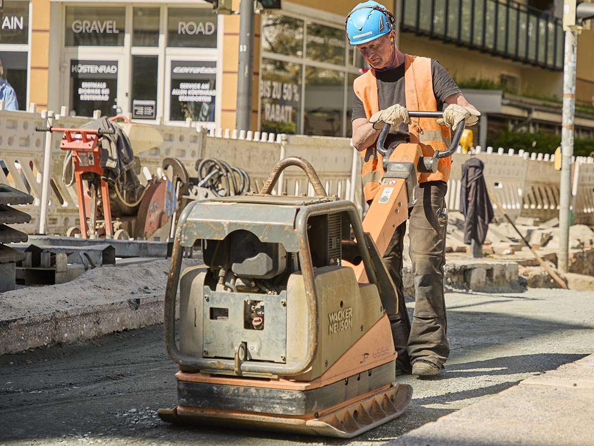 Verdichten des Unterbaus mit der Rüttelplatte auf einer innerstädtischen Baustelle